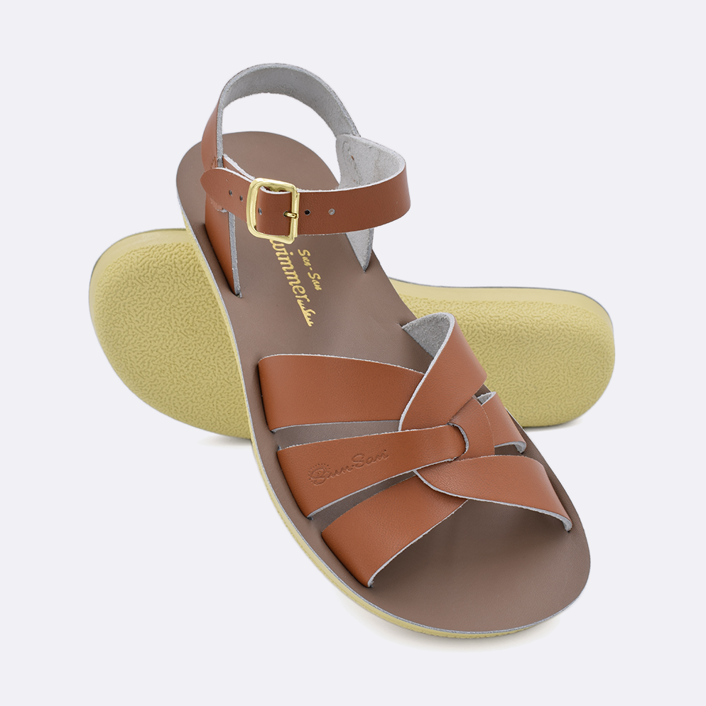 Two women's sized 8000 Swimmer style sandals with tan straps and beige insoles.  One standing with the sole facing the camera. The second is laying diagonally over the top left edge of the sole.